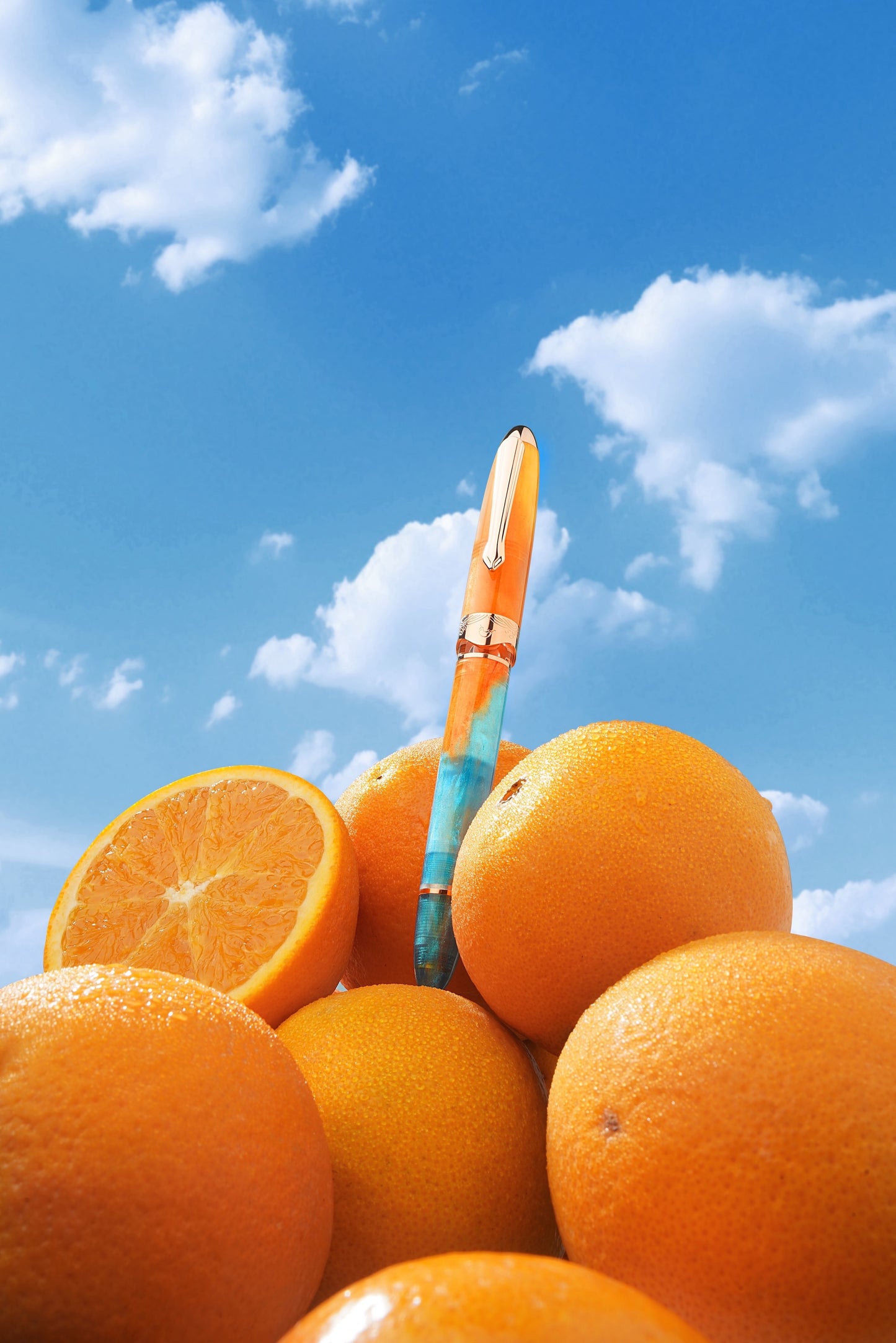Oranges with a pen on top against a blue sky