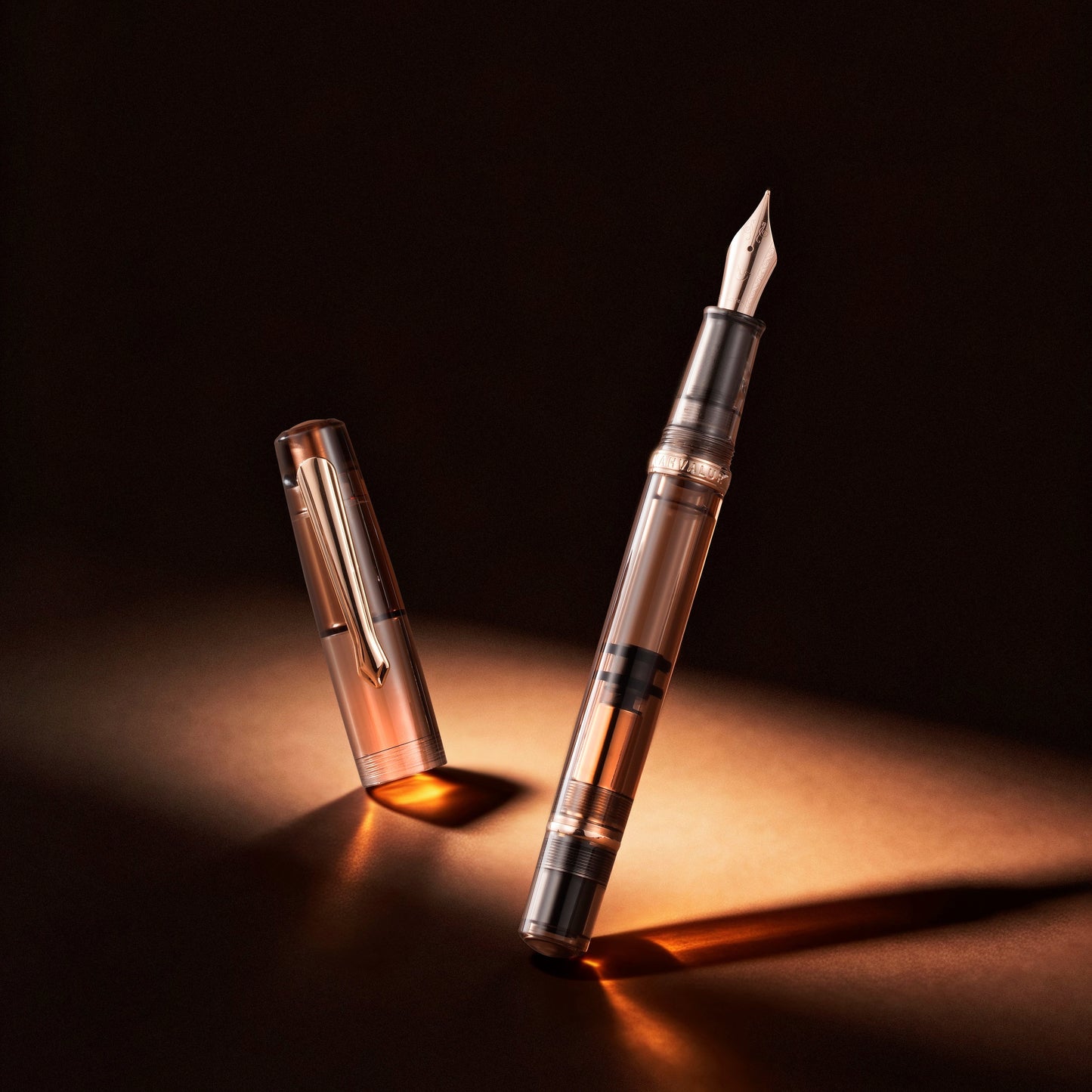 
                  
                    A transparent fountain pen with a silver nib and black accents, shown with its cap removed and standing beside it on a dark surface under dramatic warm lighting.
                  
                