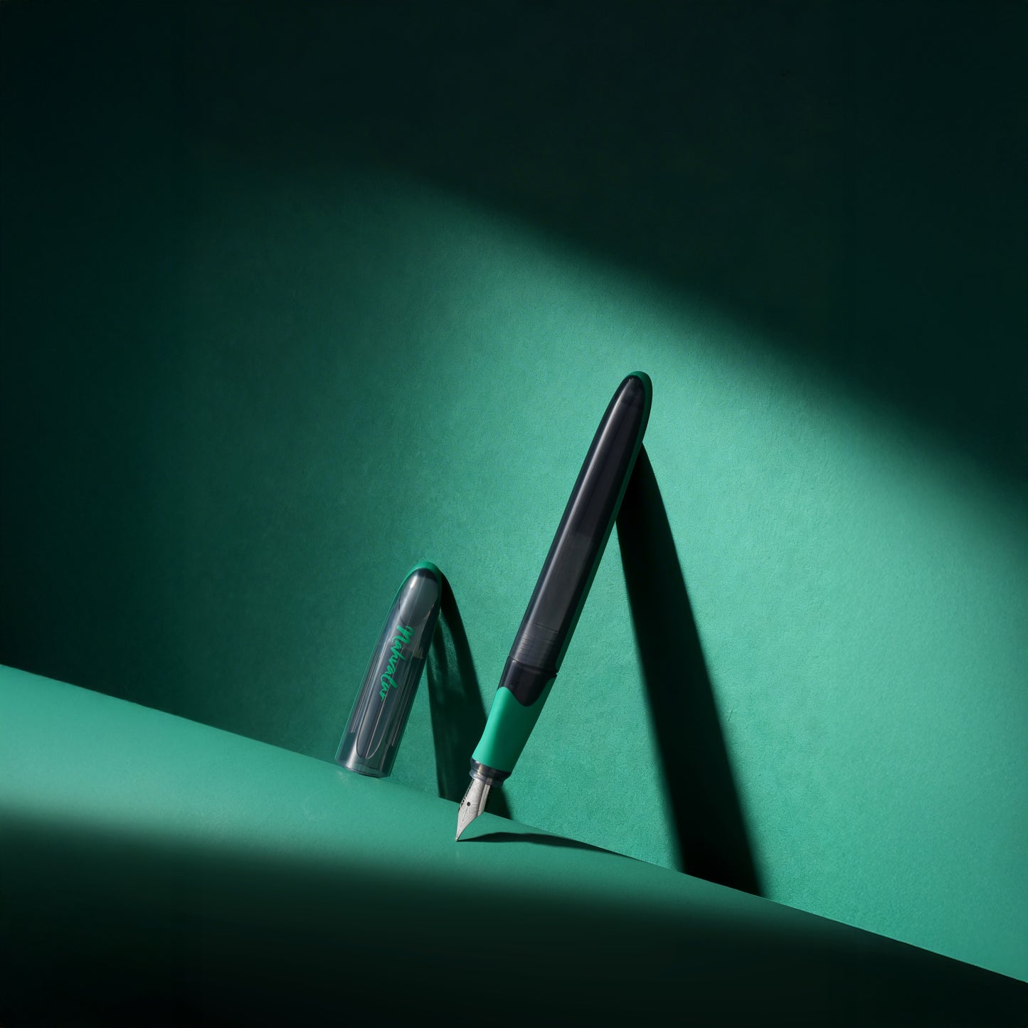 Two fountain pens on a green surface with a dark background