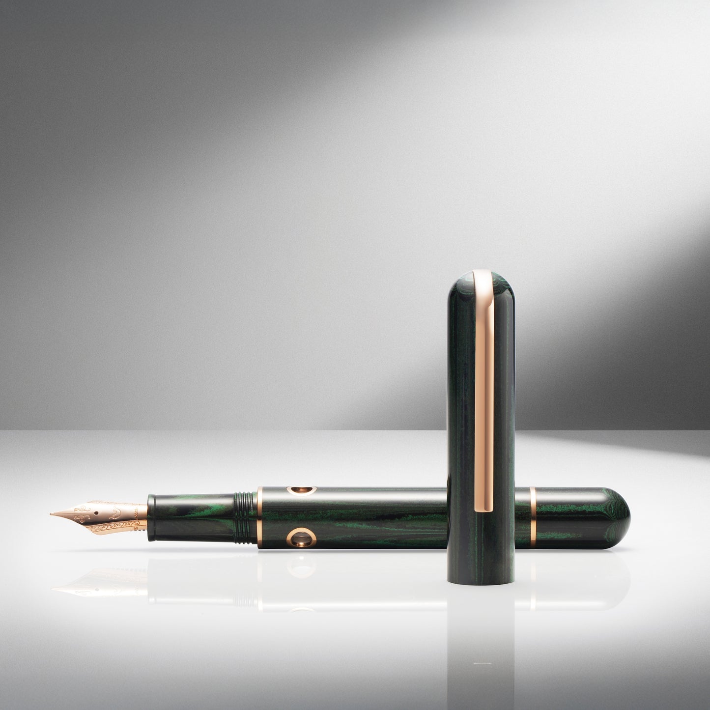 Green fountain pen with gold accents on a reflective surface