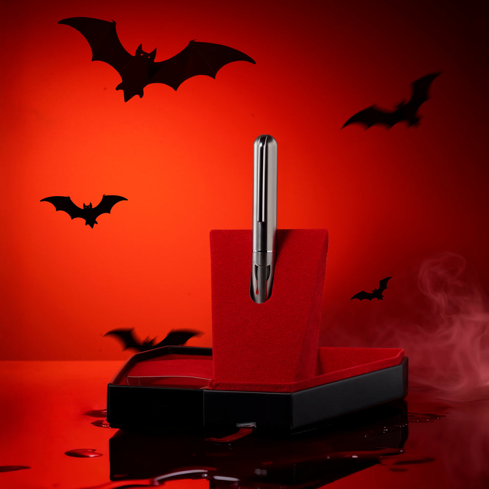 
                  
                    Dracula pen holder with a pen on an orange background with black bats
                  
                