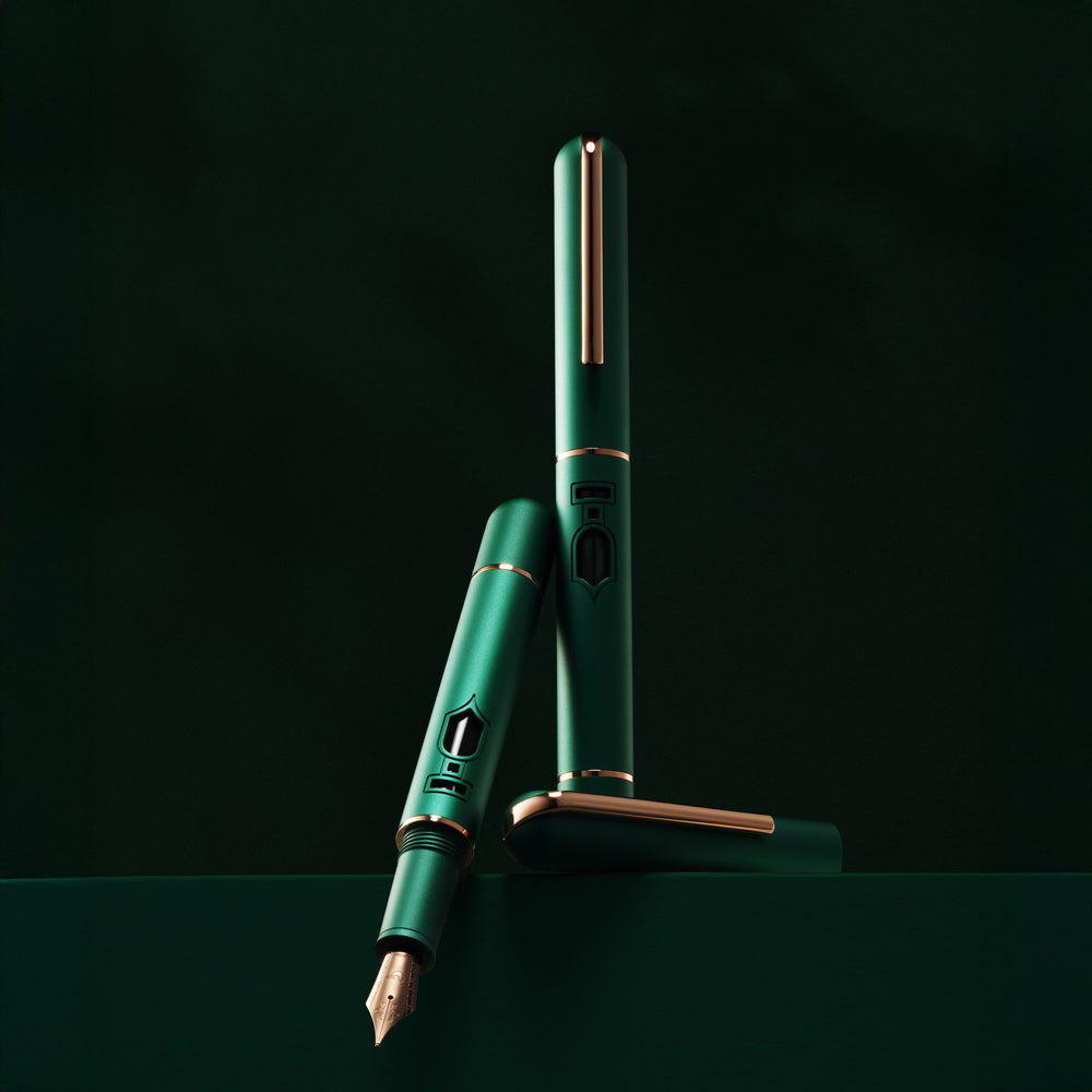 
                  
                    Green fountain pen with gold accents on a dark background
                  
                